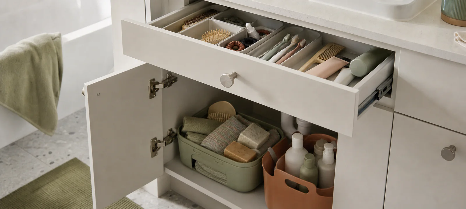 An open bathroom vanity drawer and cupboard with everyday products sorted into trays and portable caddies