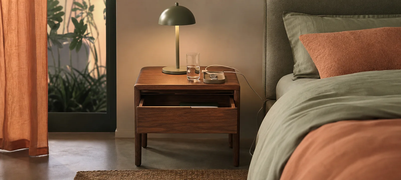 A calm bedroom with a practical bedside table, lamp and soft bedding