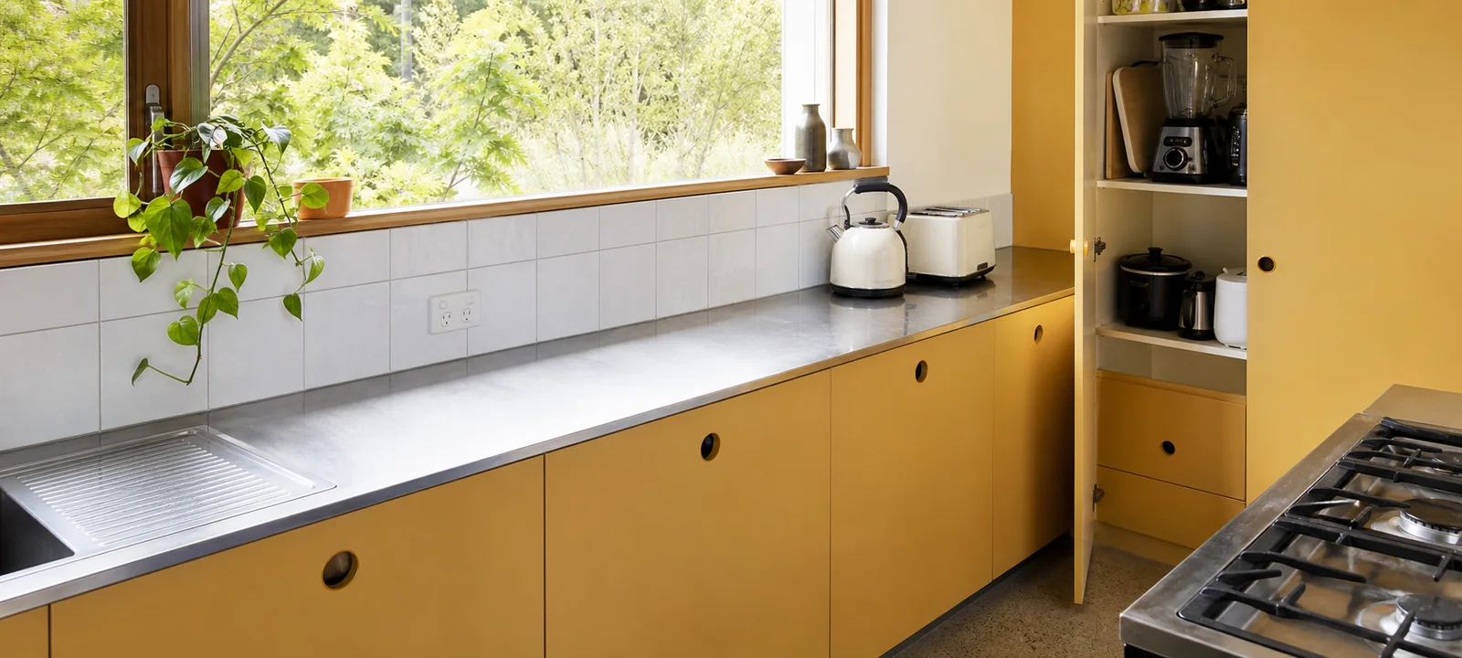 A warm kitchen with clear bench space, timber cabinetry and green accents